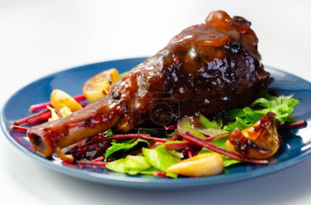 Photo for Delicious Lamb shank with red wine and rosemary gravy served on the mixed leaf salad, on the blue plate, an exclusive dish - Royalty Free Image