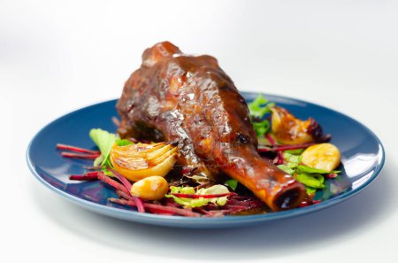 Foto de Delicioso vástago de cordero con vino tinto y salsa de romero servido en la ensalada de hojas mixtas, en el plato azul, un plato exclusivo - Imagen libre de derechos