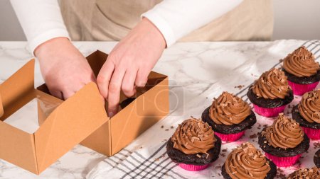 Téléchargez les photos : Pas à pas. Emballage de cupcakes au chocolat avec glaçage ganache au chocolat dans une boîte à cupcakes en papier. - en image libre de droit