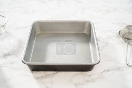 Photo for Greasing metal square baking pan to bake sweets. - Royalty Free Image