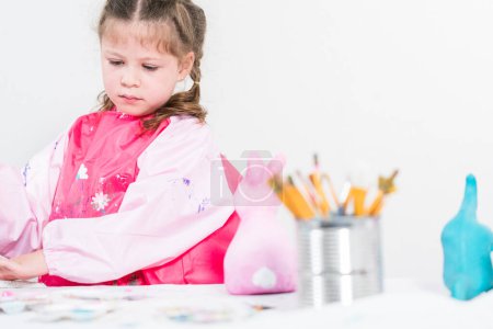 Photo for Homeschooling during COVID-19 lockdown. Little girl painting paper mache Easter bunny figurine with acrylic paint. - Royalty Free Image