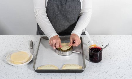 Téléchargez les photos : Remplissage de pâte empanada avec garniture tarte aux myrtilles pour faire des empanadas sucrés aux myrtilles. - en image libre de droit