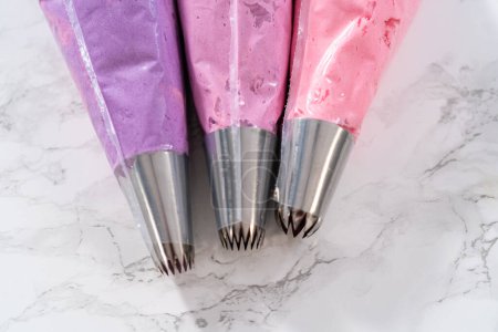 Photo for Ombre pink buttercream frosting in a piping bag with a jumbo metal piping tip. - Royalty Free Image