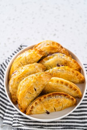 Foto de Empanadas dulces recién horneadas con arándanos en el mostrador de la cocina. - Imagen libre de derechos