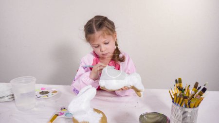 Photo for Little girl painting paper mache figurine at homeschooling art class. - Royalty Free Image