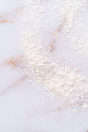 Téléchargez les photos : Farine blanche saupoudrée sur la surface de marbre rose pendant la cuisson. - en image libre de droit