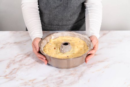 Pâte à gâteau dans une casserole à gâteau bundt pour cuire le gâteau bundt aux pommes avec glaçure au caramel.