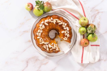 Photo for Flat lay. Slicing homemade apple bundt cake and garnishing with sliced almonds. - Royalty Free Image