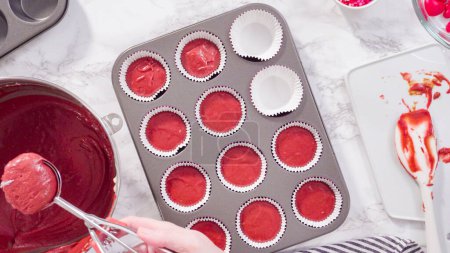 Flat lay. Step by step. Scooping cupcake batter into foil cupcake cups to bake red velvet cupcakes.