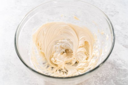 Photo for Mixing ingredients with a hand mixer in a large mixing bowl to make cream cheese frosting for carrot bundt cake. - Royalty Free Image