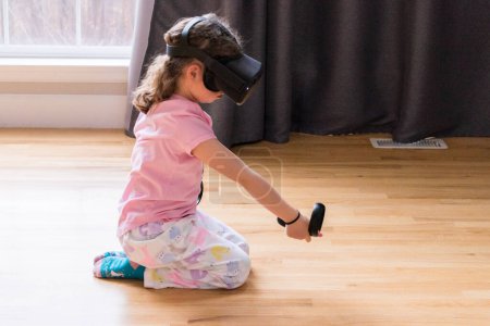 Téléchargez les photos : Petite fille jouant jeu de réalité virtuelle dans le salon, - en image libre de droit