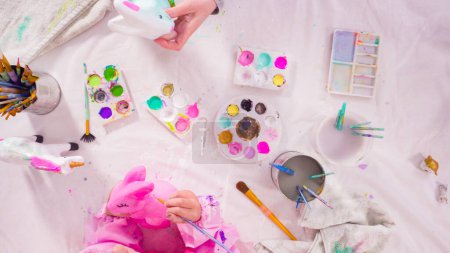 Photo for Flat lay. Little girl painting paper mache figurines with acrylic paint for her homeschooling art project. - Royalty Free Image