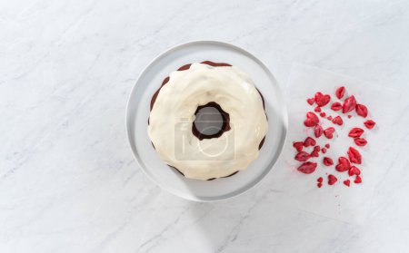 Photo for Flat lay. Decorating red velvet bundt cake with chocolate lips and hearts over cream cheese glaze. - Royalty Free Image