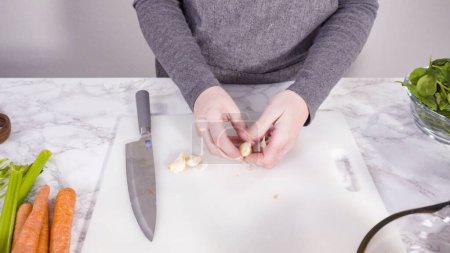 Foto de Curando verduras en una tabla de cortar blanca para cocinar sopa vegetariana de frijoles blancos. - Imagen libre de derechos