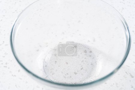 Foto de Levantamiento de la masa en un recipiente de mezcla de vidrio para hornear bañadores naan. - Imagen libre de derechos