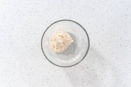 Foto de Acostado. Mezclar los ingredientes con una cuchara de madera en un tazón de vidrio grande para hornear bañadores de naan. - Imagen libre de derechos
