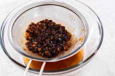 Draining freshly cooked boba pearls through a mesh strainer.