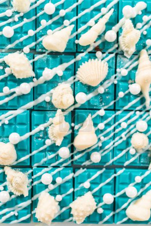Photo for Mini mermaid chocolate bars drizzled with white chocolate, sprinkling with white pearl sugar sprinkles, and decorated with a white chocolate seashells. - Royalty Free Image