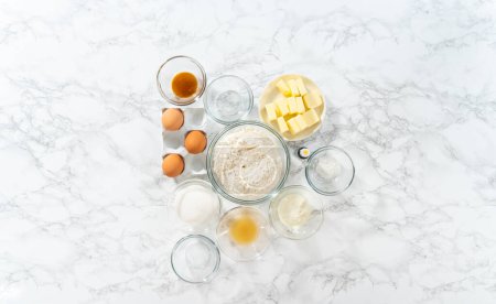 Photo for Flat lay. Lemon wedge cookies with lemon glaze. Measured ingredients in glass mixing bowls to prepare lemon wedge cookies. - Royalty Free Image