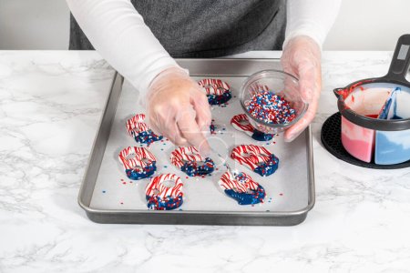 Foto de Flat lay. Dipping pretzels twists into melted chocolate to make red, white, and blue chocolate-covered pretzel twists. - Imagen libre de derechos