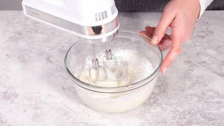 Photo for Step by step. Mixing ingredients in a glass mixing bowl to prepare cream cheese frosting. - Royalty Free Image