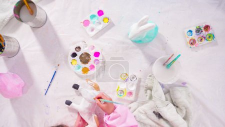 Photo for Flat lay. Little girl painting paper mache figurine at homeschooling art class. - Royalty Free Image