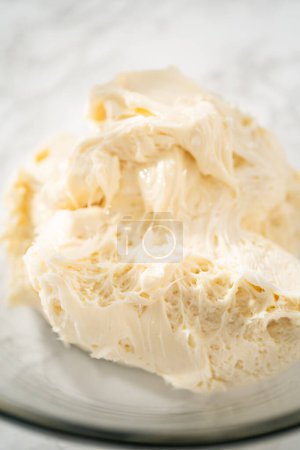 Foto de Batiendo crema de mantequilla glaseado en un tazón de vidrio con una batidora eléctrica para preparar el glaseado de crema de mantequilla de menta. - Imagen libre de derechos