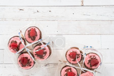 Foto de Acostado. Embalaje gourmet cupcakes de frambuesa de chocolate en cajas de plástico transparente. - Imagen libre de derechos