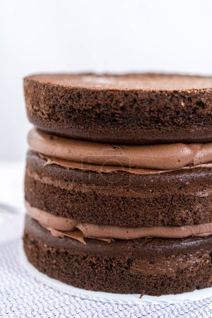 Photo for Covering chocolate cake with a crumb layer of chocolate buttercream frosting. - Royalty Free Image