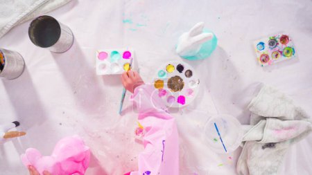 Photo for Flat lay. Little girl painting paper mache figurines with acrylic paint for her homeschooling art project. - Royalty Free Image