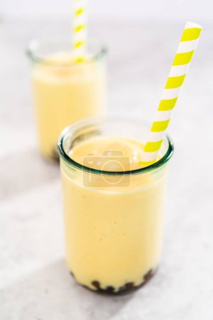 Photo for Freshly made mango boba smoothie in a drinking glass with a paper straw. - Royalty Free Image