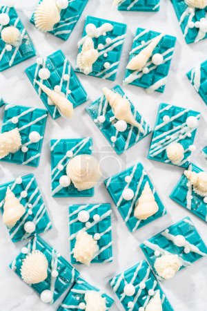 Photo for Mini mermaid chocolate bars drizzled with white chocolate, sprinkling with white pearl sugar sprinkles, and decorated with a white chocolate seashells. - Royalty Free Image