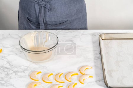 Photo for Lemon wedge cookies with lemon glaze. Dipping lemon cookies into a lemon glaze. - Royalty Free Image