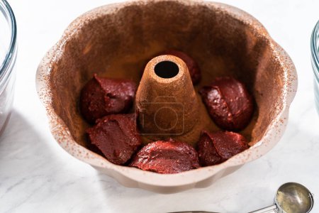 Photo for Filling metal bundt cake pan with cake butter to bake red velvet bundt cake with cream cheese glaze - Royalty Free Image