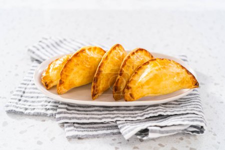 Téléchargez les photos : Empanadas de petit déjeuner fraîchement cuits avec des œufs et patates douces sur le comptoir de la cuisine. - en image libre de droit
