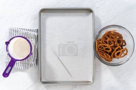 Téléchargez les photos : Flat lay. Dipping pretzels twists into melted chocolate to make chocolate-covered pretzel twists. - en image libre de droit
