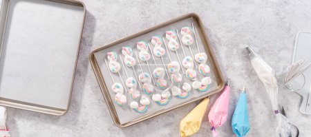 Photo for Flat lay. Unbaked unicorn theme meringue pops on a baking sheet lined with parchment paper. - Royalty Free Image