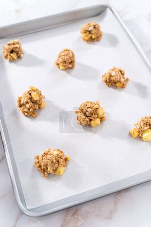 Photo for Scooping cookie dough into the baking sheet lined with parchment paper to bake apple oatmeal cookies. - Royalty Free Image