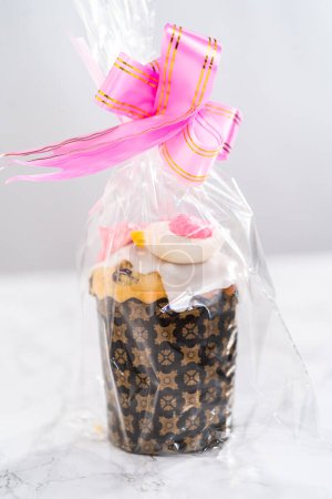 Photo for Wrapped mini Easter bread kulich with lemon glaze, decorated with sprinkles and meringue bird-shaped cookies as a good gift. - Royalty Free Image