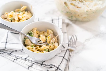 Téléchargez les photos : Servant une salade de macaronis avec poulet dans des bols en céramique blanche. - en image libre de droit