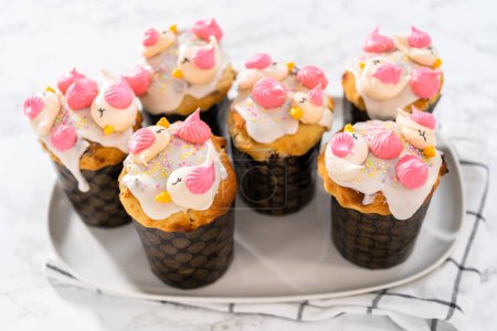Téléchargez les photos : Mini koulich de pain de Pâques fraîchement cuit avec glaçure au citron, décoré de saupoudres et de biscuits meringués en forme d'oiseau. - en image libre de droit