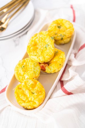 Téléchargez les photos : Muffin aux œufs au bacon et fromage dans une assiette de service blanche. - en image libre de droit