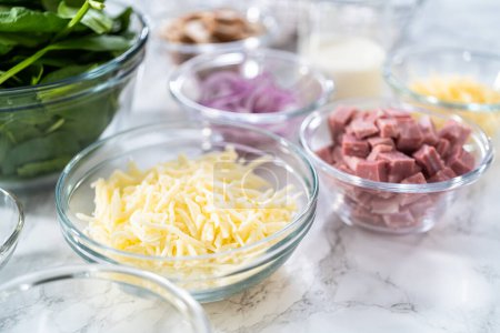 Photo for Ingredients in glass mixing bowls to prepare spinach and ham frittata. - Royalty Free Image