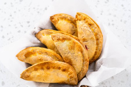 Photo for Freshly baked sweet cherry empanadas in the air fryer on the kitchen counter. - Royalty Free Image