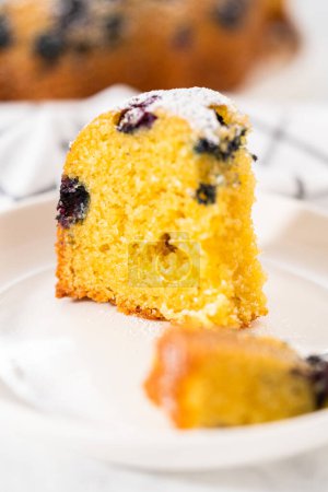 Téléchargez les photos : Trancher le gâteau de lapin de myrtille au citron fraîchement cuit avec du sucre en poudre époussetant. - en image libre de droit