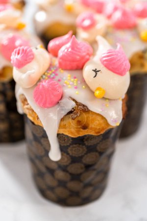 Téléchargez les photos : Mini koulich de pain de Pâques fraîchement cuit avec glaçure au citron, décoré de saupoudres et de biscuits meringués en forme d'oiseau. - en image libre de droit