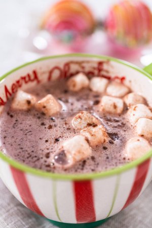 Téléchargez les photos : Préparation de bombes au chocolat chaud de Noël avec du lait chaud dans une tasse de Noël. - en image libre de droit
