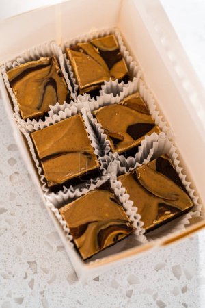Téléchargez les photos : Emballage de caramel au chocolat fait maison avec du beurre d'arachide tourbillonner dans une boîte cadeau blanche. - en image libre de droit
