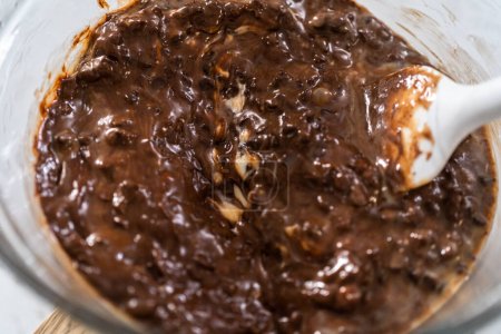 Photo for Melting chocolate chips and other ingredients in a glass mixing bowl over boiling water to prepare plain fudge. - Royalty Free Image