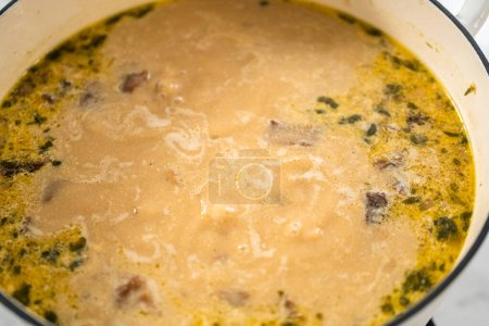 Foto de Cocinar sopa de champiñones silvestres cremosa hecha en un horno holandés esmaltado. - Imagen libre de derechos